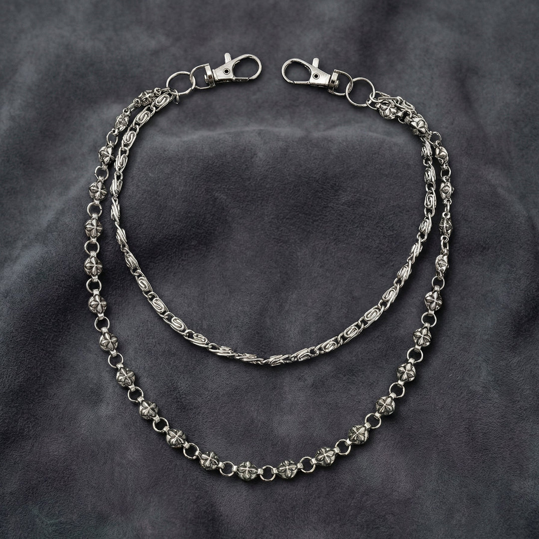 Handcrafted Manor Guardian dual-strand gothic wallet chain with ornate cross links and floral clasps draped on dark charcoal suede.