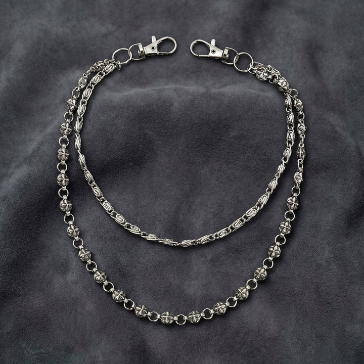 Handcrafted Manor Guardian dual-strand gothic wallet chain with ornate cross links and floral clasps draped on dark charcoal suede.