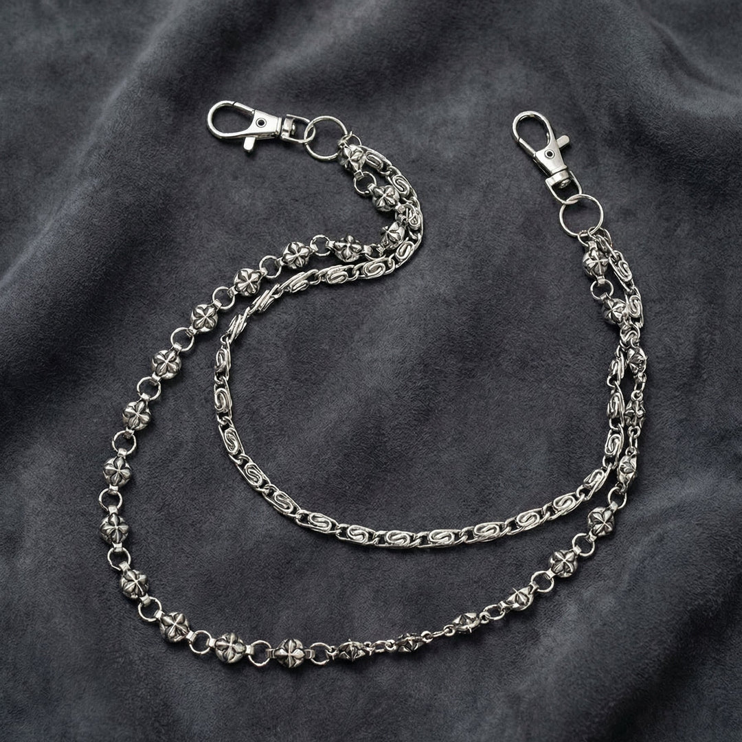 Handcrafted Manor Guardian dual-strand gothic wallet chain with ornate cross links and floral clasps draped on dark charcoal suede.