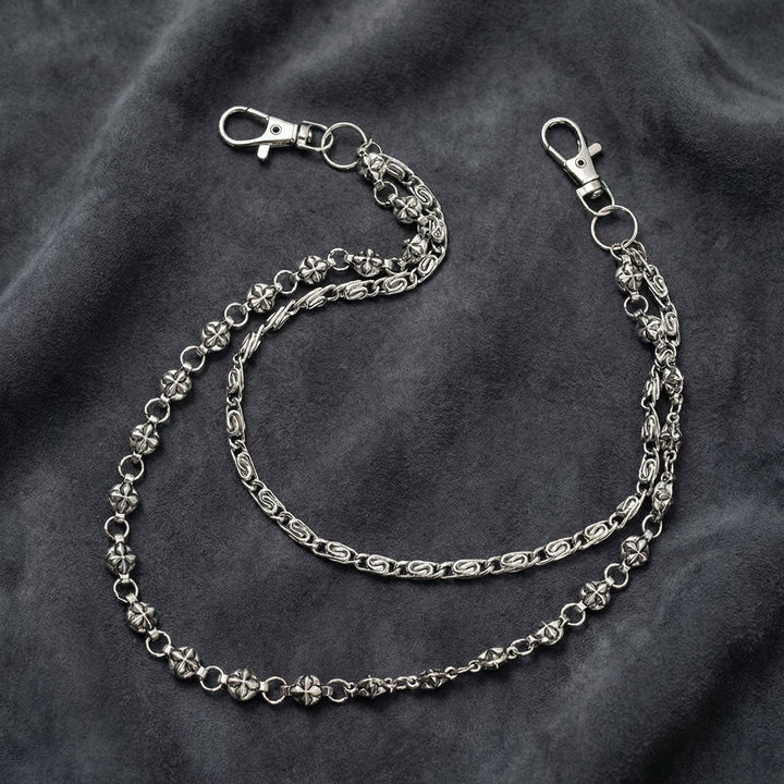 Handcrafted Manor Guardian dual-strand gothic wallet chain with ornate cross links and floral clasps draped on dark charcoal suede.