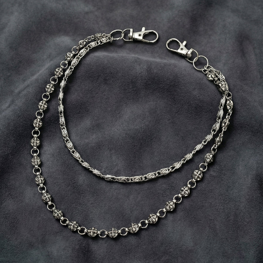 Handcrafted Manor Guardian dual-strand gothic wallet chain with ornate cross links and floral clasps draped on dark charcoal suede.