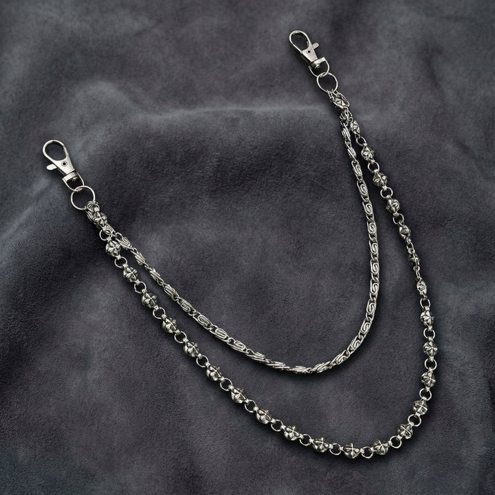 Handcrafted Manor Guardian dual-strand gothic wallet chain with ornate cross links and floral clasps draped on dark charcoal suede.