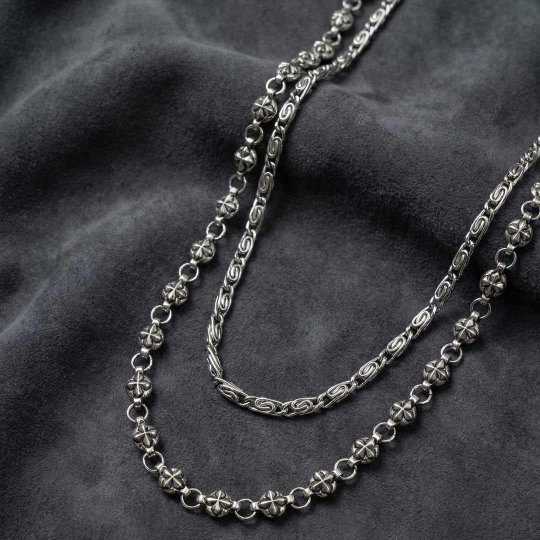 Handcrafted Manor Guardian dual-strand gothic wallet chain with ornate cross links and floral clasps draped on dark charcoal suede.
