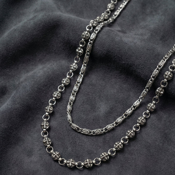 Handcrafted Manor Guardian dual-strand gothic wallet chain with ornate cross links and floral clasps draped on dark charcoal suede.
