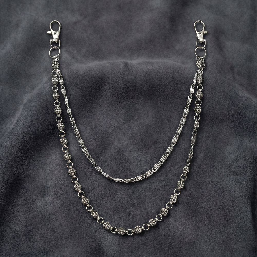 Handcrafted Manor Guardian dual-strand gothic wallet chain with ornate cross links and floral clasps draped on dark charcoal suede.