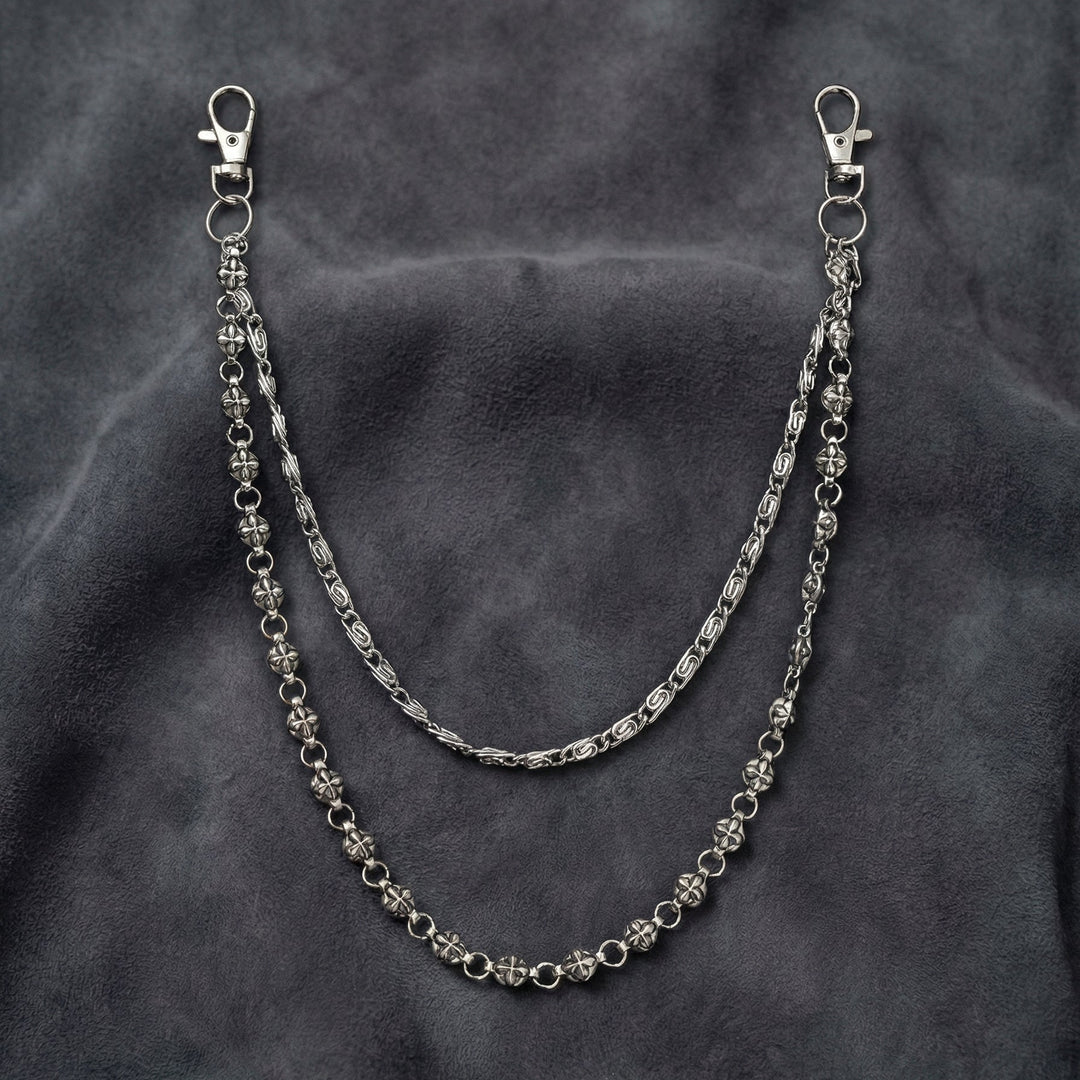Handcrafted Manor Guardian dual-strand gothic wallet chain with ornate cross links and floral clasps draped on dark charcoal suede.