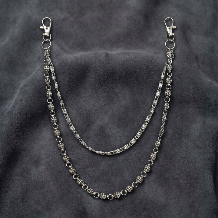 Handcrafted Manor Guardian dual-strand gothic wallet chain with ornate cross links and floral clasps draped on dark charcoal suede.