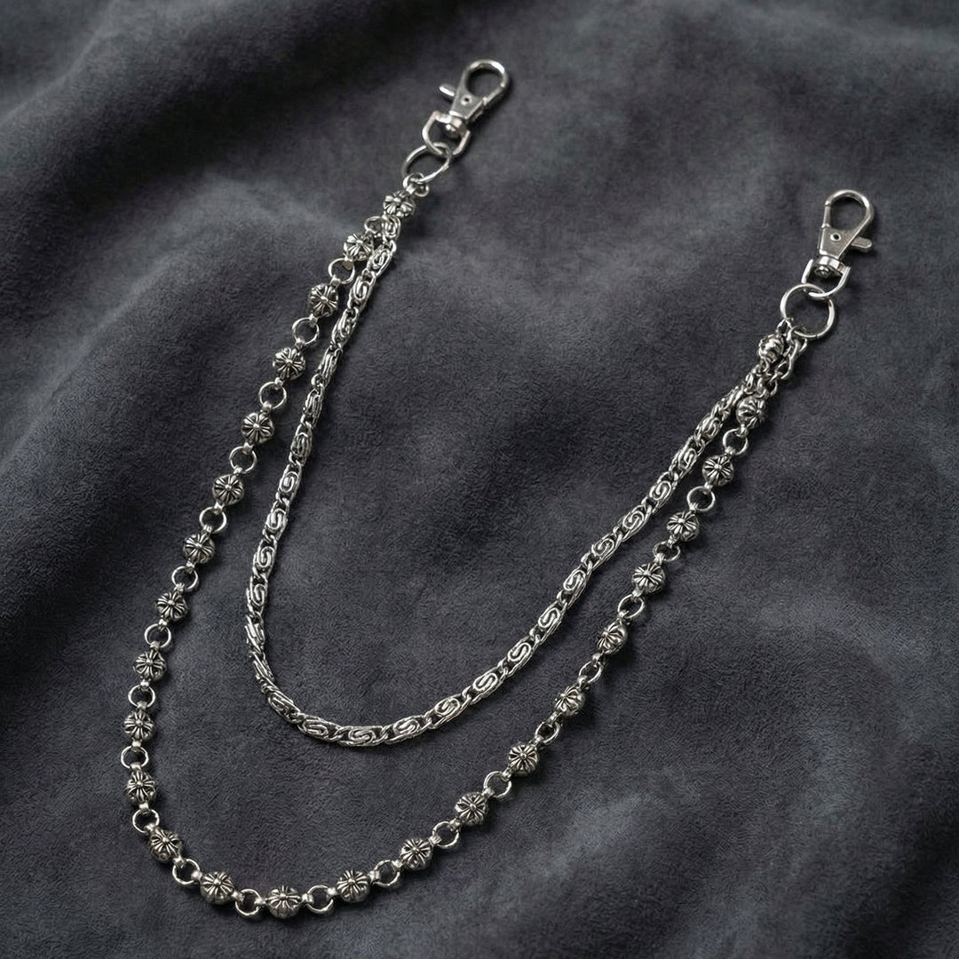 Handcrafted Manor Guardian dual-strand gothic wallet chain with ornate cross links and floral clasps draped on dark charcoal suede.