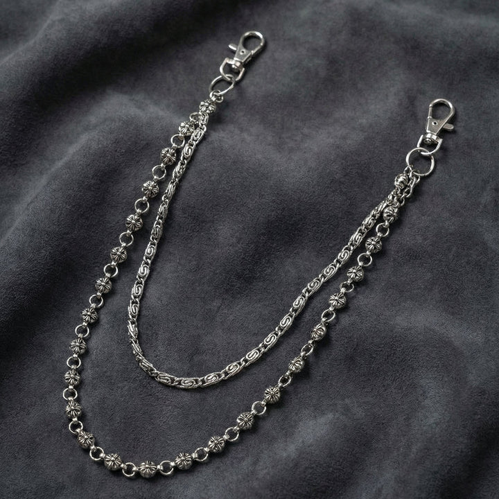 Handcrafted Manor Guardian dual-strand gothic wallet chain with ornate cross links and floral clasps draped on dark charcoal suede.
